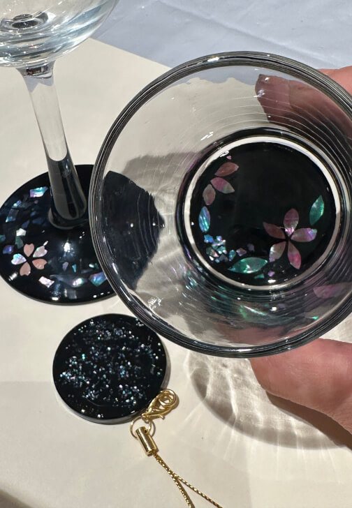 A wine glass, a tumbler and a round wine marker, all with shell patterns on black