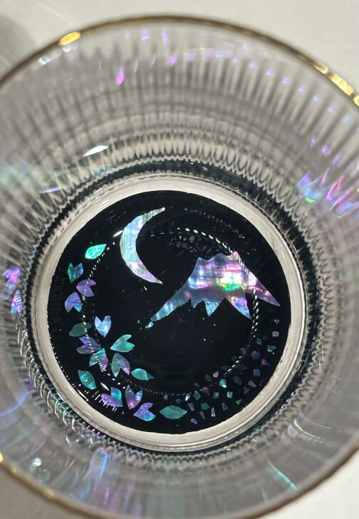 Mt Fuji and a crescent moon inlaid in shell at the bottom of a glass, ringed with cherry blossoms