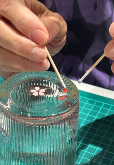 Placing a tiny shell cherry blossom into the base of a glass with a fine stick